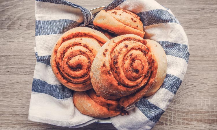 Aerial view of 5 spiral dinner rolls in a basket with a striped blue and white cloth