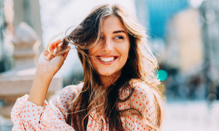 Brunette woman with a polka-dot blouse smiles with porcelain veneers