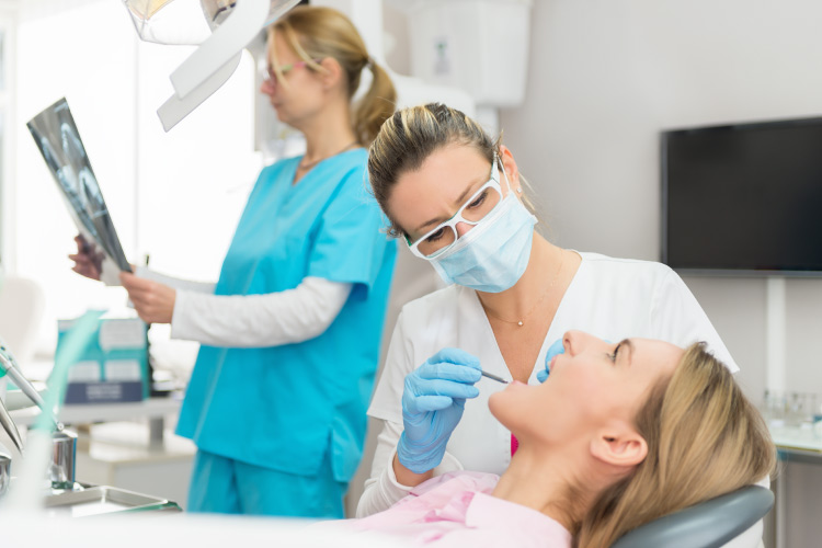 Dental professional examines the mouth of a woman to determine if she needs her wisdom teeth removed