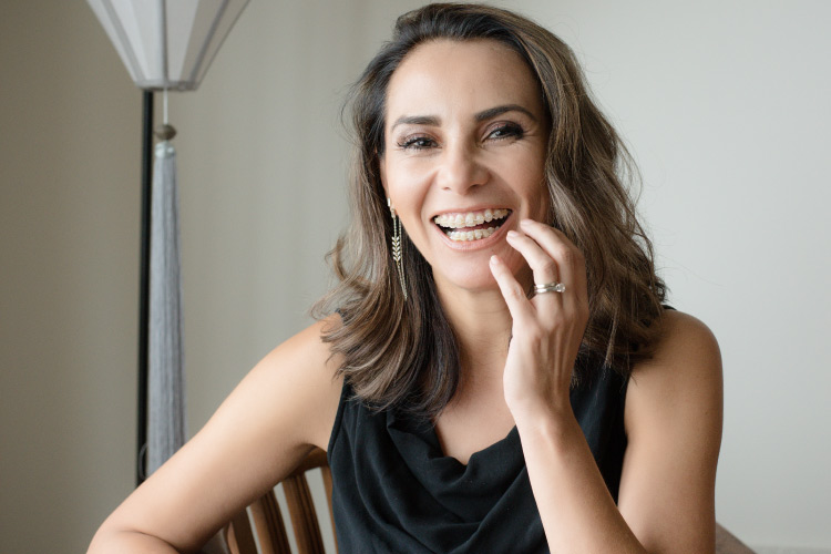 Brunette woman with braces smiles and commits to wearing her retainer after her braces come off