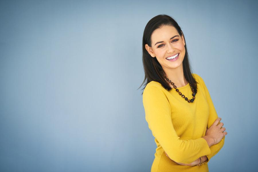 Brunette woman with veneers smiles in a yellow blouse in Fayetteville, AR