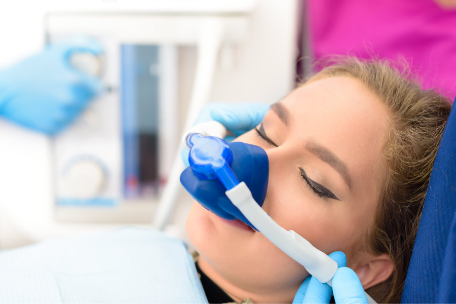 Brunette woman relaxes while receiving nitrous oxide through a nose mask at the dentist in Fayetteville, AR