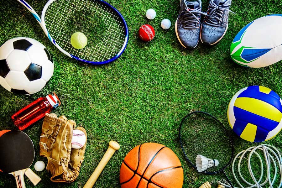Looking down onto a green field on a circle of sports equipment that could cause sports-related dental injuries