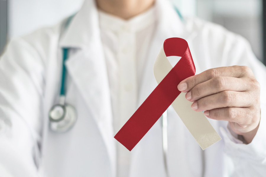 Closeup of a dentist holding a beige and maroon ribbon that indicates oral cancer awareness